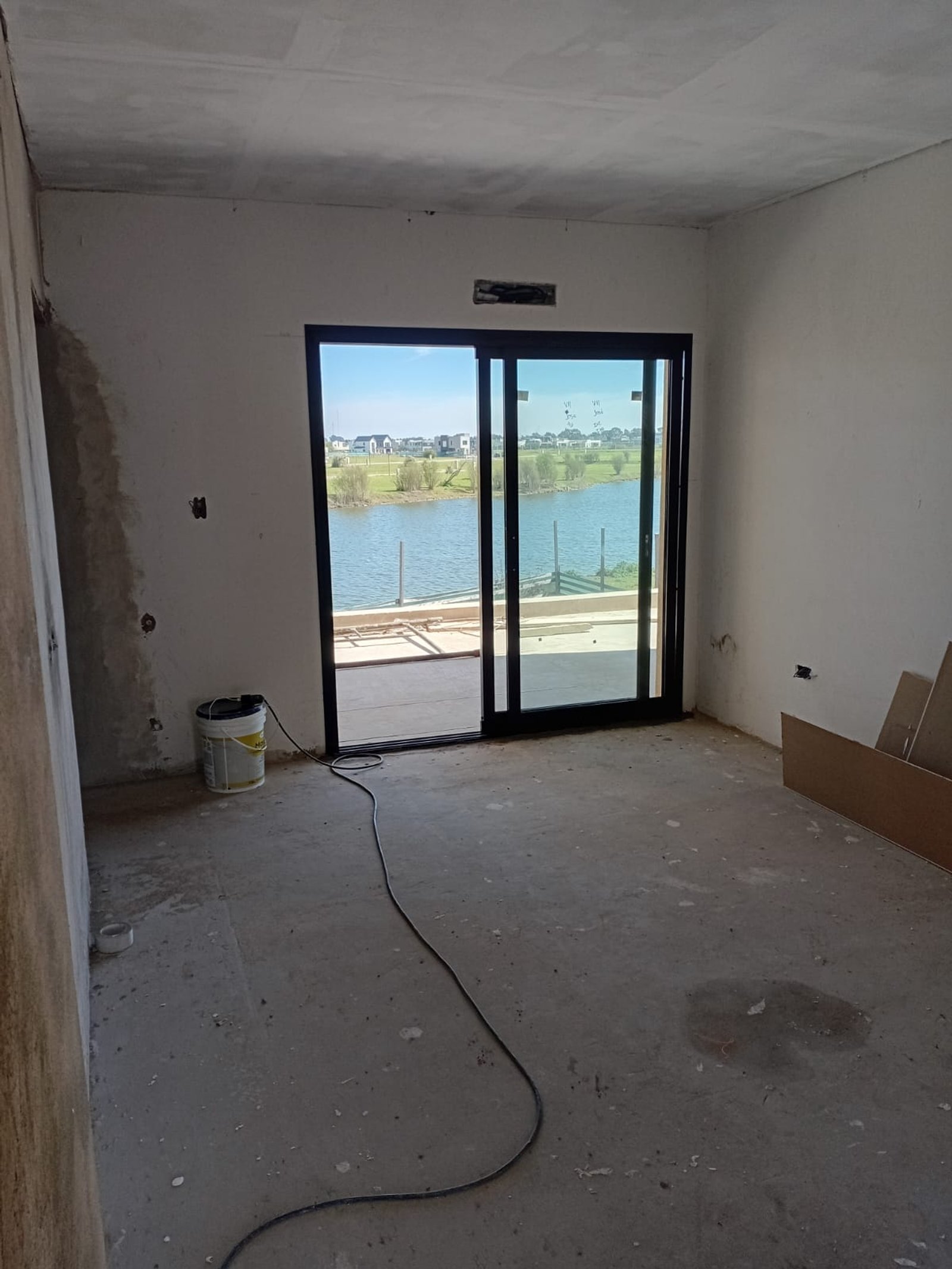 Interior de construcción con grandes ventanales y vista al agua — proyecto Casa en Pueblos del Plata, por Arquitecto Guido Niccoli, en Guillermo Enrique Hudson